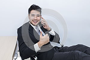 Young handsome businessman smiling and talking with phone at office