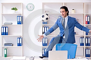 The young handsome businessman with soccer ball in the office