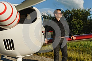 Young handsome businessman is standing near private plane. Confident and successful man in airport