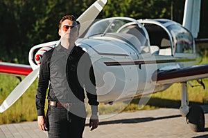 Young handsome businessman is standing near private plane. Confident and successful man in airport