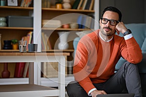 Young handsome businessman thinking business strategies while sitting on floor in living room