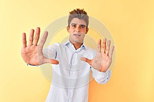 Young handsome businessman wearing elegant shirt over isolated yellow background afraid and terrified with fear expression stop