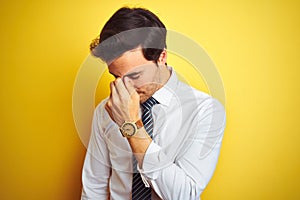 Young handsome businessman wearing elegant shirt and tie over isolated yellow background tired rubbing nose and eyes feeling