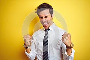 Young handsome businessman wearing elegant shirt and tie over isolated yellow background very happy and excited doing winner