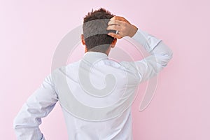 Young handsome businessman wearing shirt and tie standing over isolated pink background Backwards thinking about doubt with hand