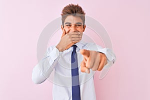 Young handsome businessman wearing shirt and tie standing over isolated pink background laughing at you, pointing finger to the