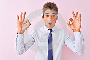 Young handsome businessman wearing shirt and tie standing over isolated pink background looking surprised and shocked doing ok