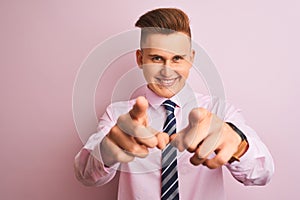 Young handsome businessman wearing shirt and tie standing over isolated pink background pointing to you and the camera with