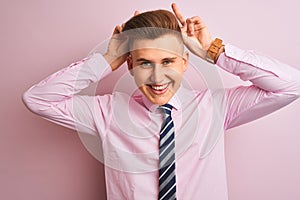 Young handsome businessman wearing shirt and tie standing over isolated pink background Posing funny and crazy with fingers on