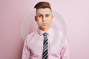 Young handsome businessman wearing shirt and tie standing over isolated pink background puffing cheeks with funny face