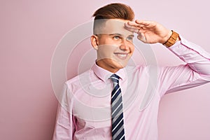 Young handsome businessman wearing shirt and tie standing over isolated pink background very happy and smiling looking far away