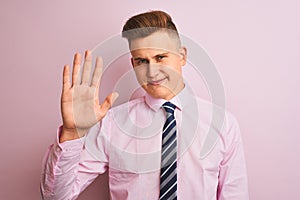 Young handsome businessman wearing shirt and tie standing over isolated pink background Waiving saying hello happy and smiling,