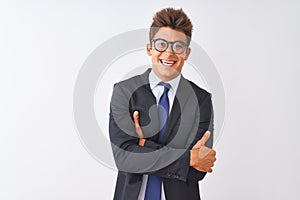 Young handsome businessman wearing suit and glasses over isolated white background happy face smiling with crossed arms looking at