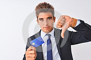 Young handsome businessman wearing suit holding credit card over isolated white background with angry face, negative sign showing