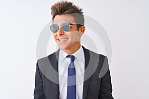 Young handsome businessman wearing suit and sunglasses over isolated white background looking away to side with smile on face,
