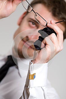 Young handsome businessman wiping eyeglasses