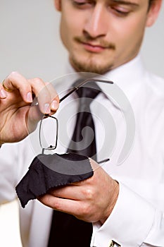 Young handsome businessman wiping eyeglasses