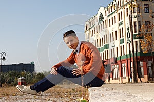 Young handsome casual man sitting on the sidewalk in old city a