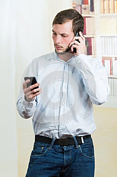 Young handsome casual man using two cell phones