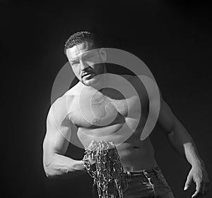 Young handsome caucasian bodybuilder sportsman working out with chain in gym, doing biceps training.