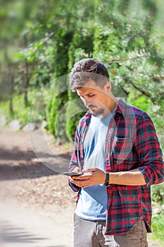 Young handsome Caucasian man with a beard and mustache writes on the phone. Modern man with a gadget, chatting, sending messages