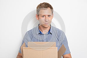 A young handsome caucasian man holding an open cardboard box in his hands and smiled