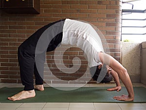 Young handsome caucasian man practicing yoga, bridge or wheel yoga pose