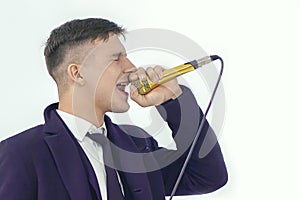 Young handsome caucasian man sings into golden microphone with closed eyes and passion. Concept of party or karaore vocal.