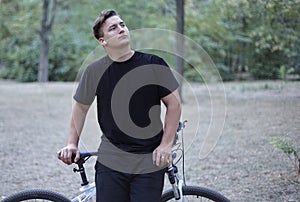 Young handsome caucasian man stands with his bicycle in a model style.