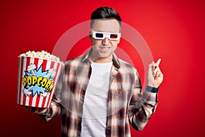 Young handsome caucasian man wearing 3d movie glasses and eating popcorn Pointing aside worried and nervous with forefinger,