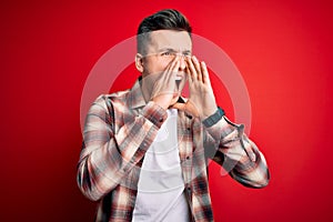 Young handsome caucasian man wearing casual modern shirt over red isolated background Shouting angry out loud with hands over