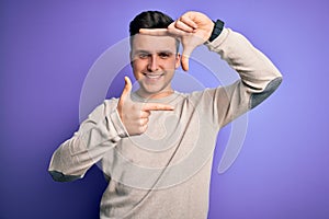 Young handsome caucasian man wearing casual sweater over purple isolated background smiling making frame with hands and fingers