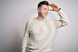 Young handsome caucasian man wearing casual winter sweater over white isolated background very happy and smiling looking far away