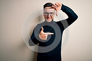 Young handsome caucasian man wearing glasses and casual sweater over isolated background smiling making frame with hands and