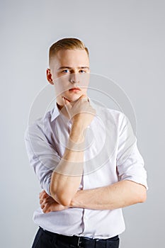 Young handsome caucasian man in white shirt touches his chin