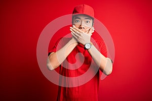 Young handsome chinese delivery man wearing cap standing over isolated red background shocked covering mouth with hands for
