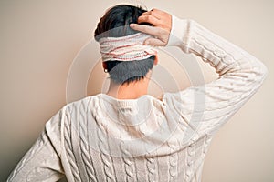 Young handsome chinese man injured for accident wearing bandage and strips on head Backwards thinking about doubt with hand on