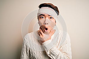 Young handsome chinese man injured for accident wearing bandage and strips on head Looking fascinated with disbelief, surprise and