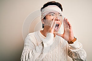 Young handsome chinese man injured for accident wearing bandage and strips on head Shouting angry out loud with hands over mouth
