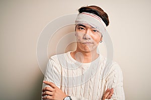 Young handsome chinese man injured for accident wearing bandage and strips on head skeptic and nervous, disapproving expression on