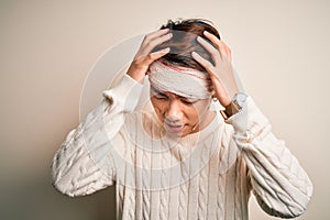 Young handsome chinese man injured for accident wearing bandage and strips on head suffering from headache desperate and stressed