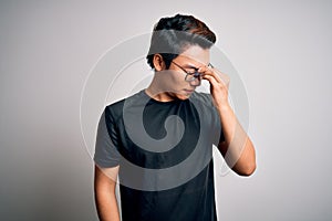 Young handsome chinese man wearing black t-shirt and glasses over white background tired rubbing nose and eyes feeling fatigue and