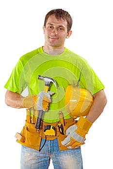 a young handsome construction contractor with tools standing holding claw hammer and helmet looking at camera isolated