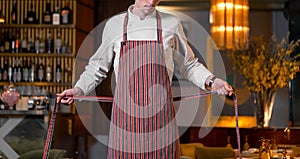 Young handsome cook chief tying apron in modern restaurant interior