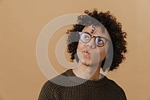 Young handsome curly thoughtful boy in glasses with puckered lips