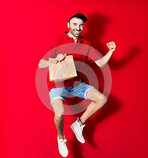 Young handsome deliveryman wearing cap smiling happy