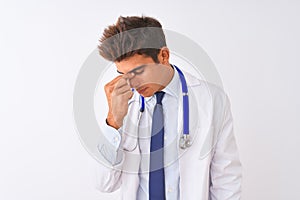 Young handsome doctor man wearing stethoscope over isolated white background tired rubbing nose and eyes feeling fatigue and