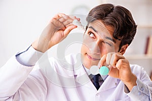 Young handsome doctor ophthalmologist with contact lenses in hos
