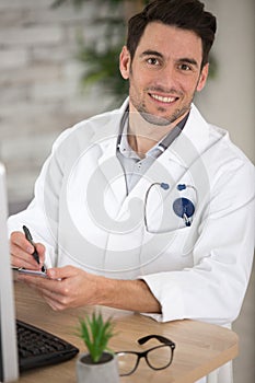 young handsome doctor writing in office