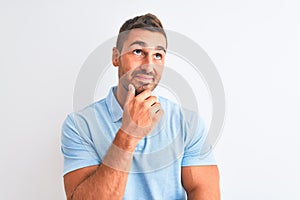 Young handsome elegant man wearing blue t-shirt over  background with hand on chin thinking about question, pensive